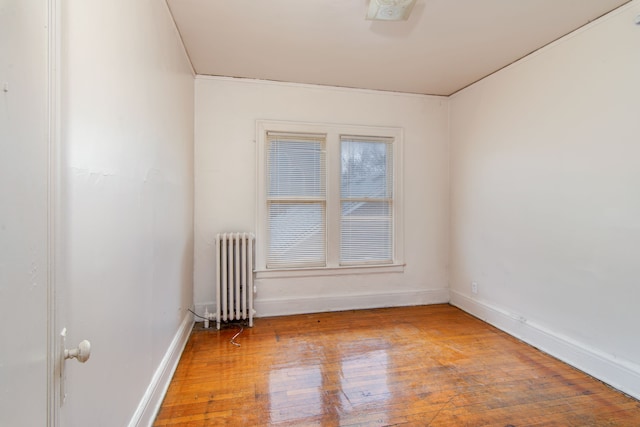 empty room with radiator, baseboards, and wood-type flooring