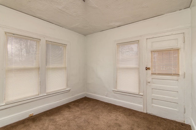 empty room with baseboards, a textured ceiling, and dark carpet
