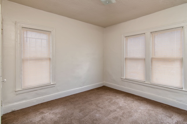 unfurnished room featuring baseboards, a textured ceiling, and carpet