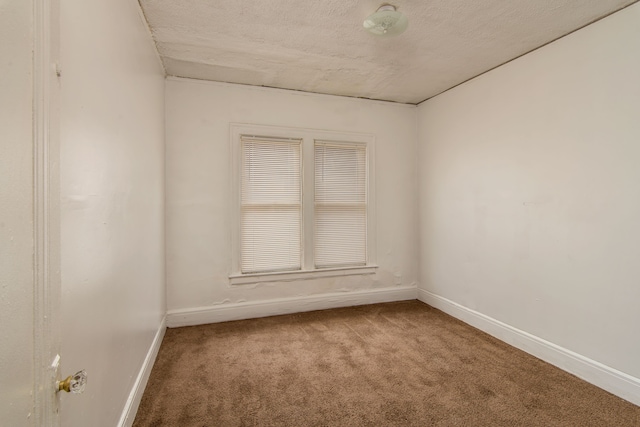 carpeted empty room featuring baseboards