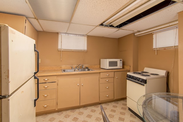 kitchen with light countertops, a sink, light floors, and white appliances