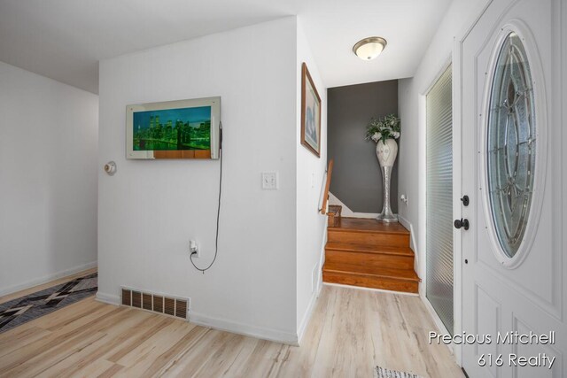 foyer featuring wood finished floors, baseboards, stairs, and visible vents