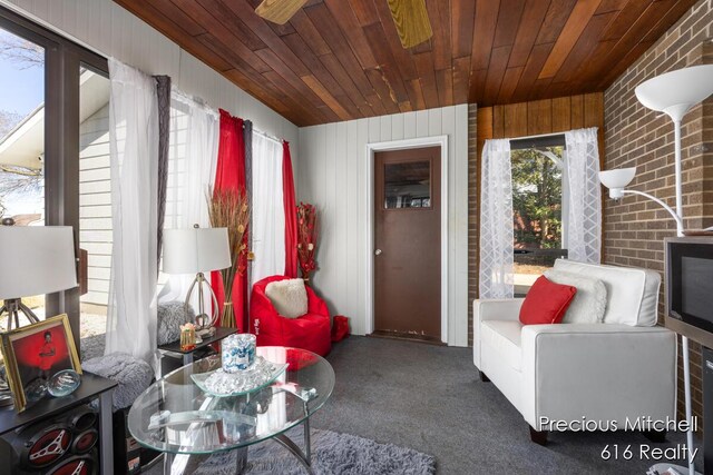 living area featuring carpet floors, wooden ceiling, and ceiling fan