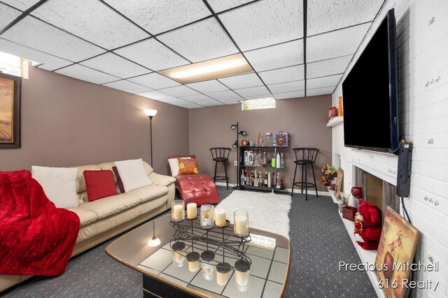 living room featuring a brick fireplace, baseboards, carpet, and a paneled ceiling