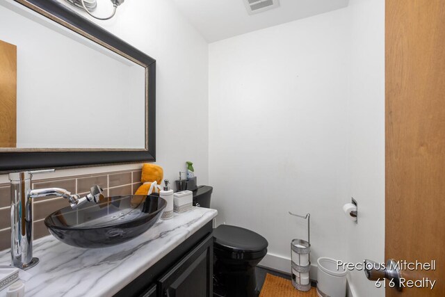 bathroom featuring toilet, vanity, and visible vents