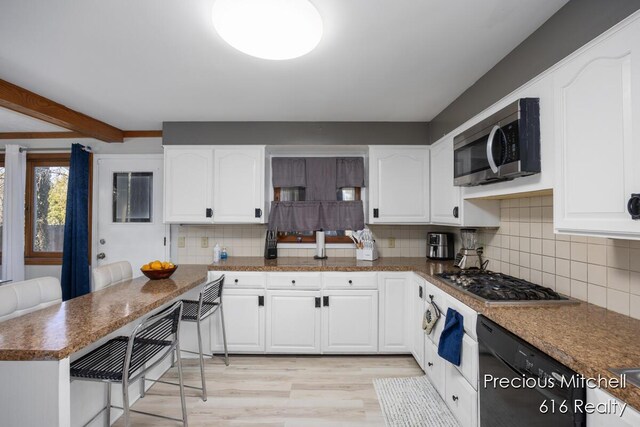 kitchen with white cabinets, light wood-style floors, backsplash, and stainless steel appliances