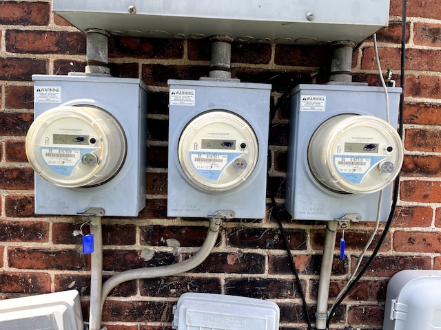 exterior details featuring electric meter, a wood stove, and brick siding