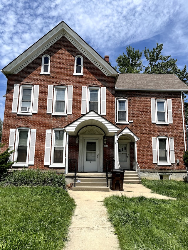 view of front facade featuring a chimney and brick siding
