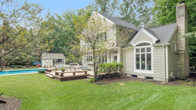 back of house featuring a yard, a chimney, an outdoor structure, and a storage unit