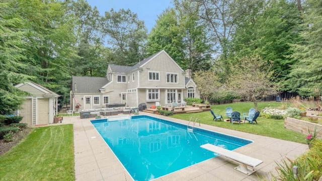 pool with a wooden deck, a patio area, an outdoor structure, an outdoor hangout area, and a yard