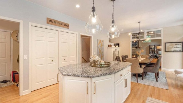 3820 Harbor Point Dr, Norton Shores, MI 49441 - kitchen with light wood-style floors, white cabinets, light stone counters, and a kitchen island