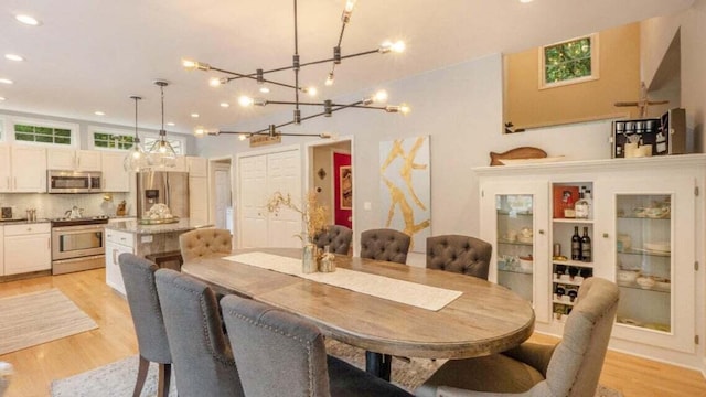 dining room with recessed lighting, light wood-type flooring, and a notable chandelier