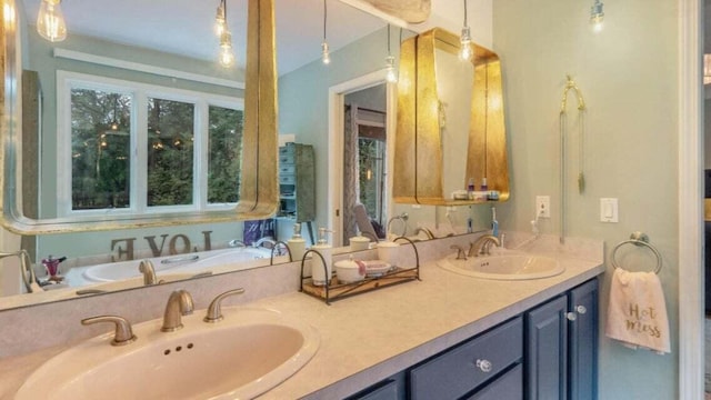 bathroom featuring double vanity, a tub, and a sink