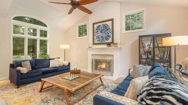 living area featuring a fireplace with flush hearth, ceiling fan, and a wealth of natural light