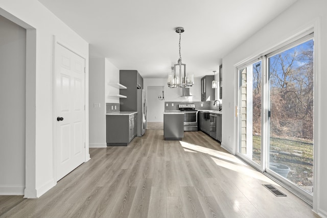 kitchen with light countertops, open shelves, an inviting chandelier, gray cabinetry, and appliances with stainless steel finishes