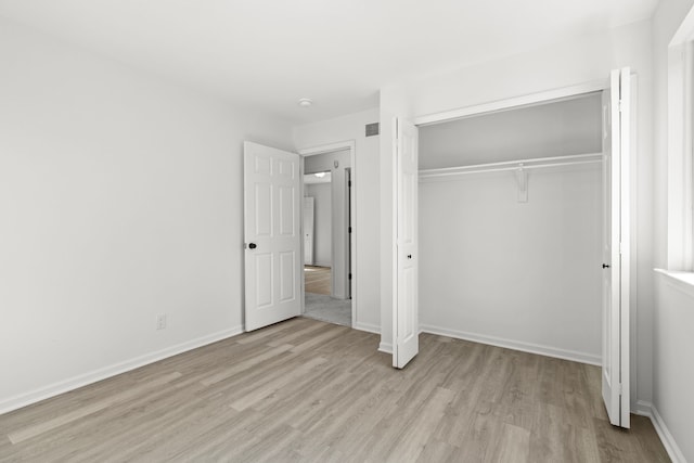 unfurnished bedroom with light wood-style flooring, baseboards, a closet, and visible vents
