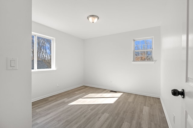 spare room featuring visible vents, baseboards, and wood finished floors