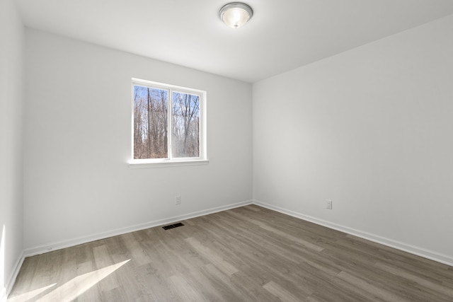 spare room featuring baseboards, visible vents, and wood finished floors