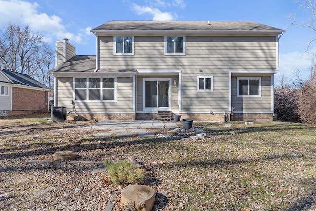 back of property with central AC unit, a lawn, a chimney, and a patio