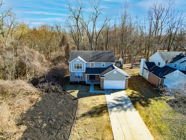 traditional-style house featuring stone siding, a front yard, concrete driveway, and an attached garage