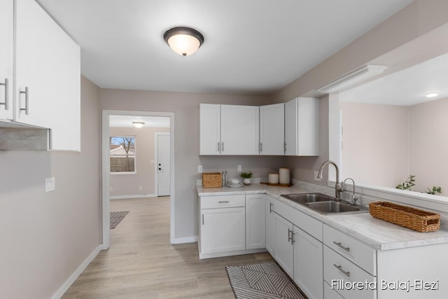 2100 Dawson Ave NE, Grand Rapids, MI 49505 - kitchen with light wood finished floors, white cabinetry, light countertops, and a sink