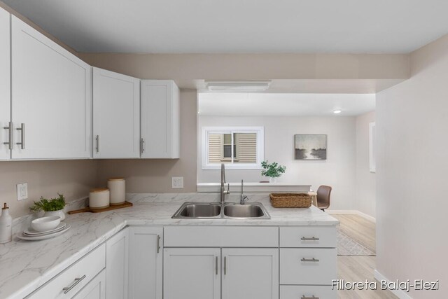 2100 Dawson Ave NE, Grand Rapids, MI 49505 - kitchen with a sink, light stone countertops, baseboards, white cabinets, and light wood-style floors