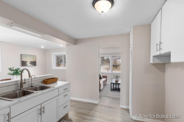 2100 Dawson Ave NE, Grand Rapids, MI 49505 - kitchen with white cabinets, light countertops, baseboards, a sink, and light wood-style floors