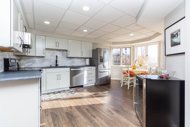 1405 S Sashabaw Rd, Ortonville, MI 48462 - kitchen featuring dark wood-style flooring, decorative backsplash, a sink, dark countertops, and appliances with stainless steel finishes