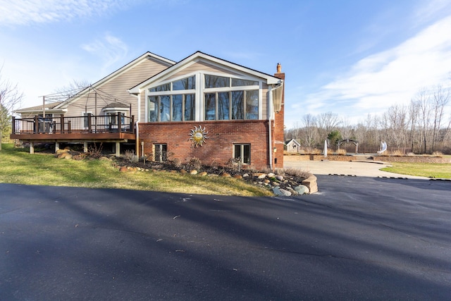 1405 S Sashabaw Rd, Ortonville, MI 48462 - exterior space with brick siding, a sunroom, a deck, and a chimney