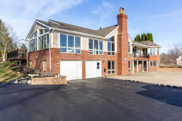 1405 S Sashabaw Rd, Ortonville, MI 48462 - exterior space featuring a chimney, an attached garage, a ceiling fan, brick siding, and driveway