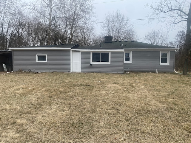 back of house featuring a lawn, a chimney, and a carport