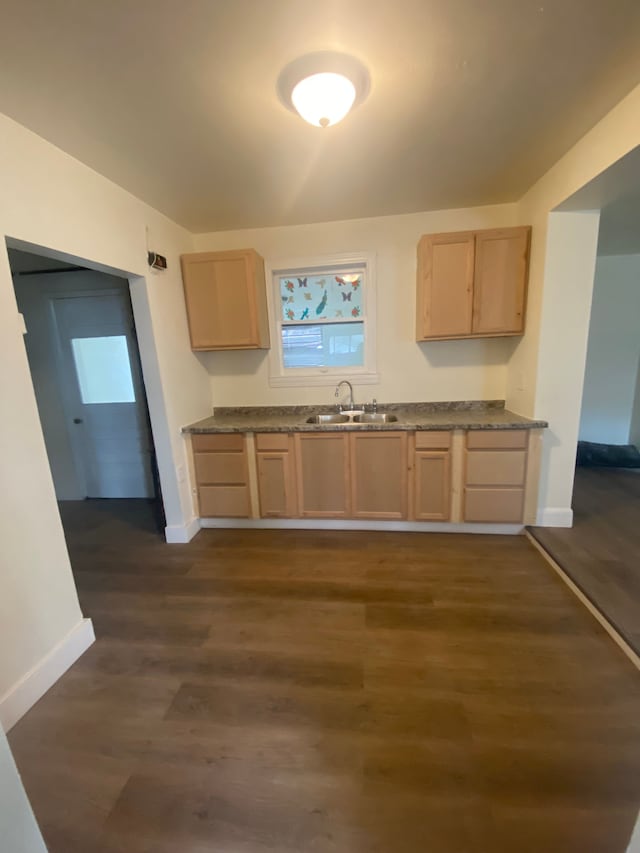 kitchen with dark countertops, light brown cabinets, baseboards, and dark wood-style floors