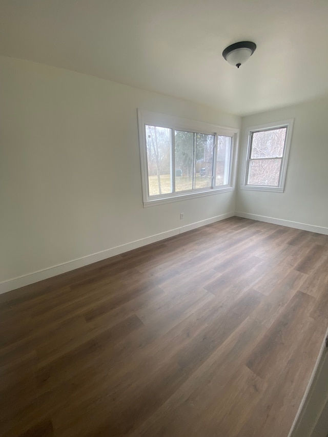 empty room with baseboards and dark wood-style floors