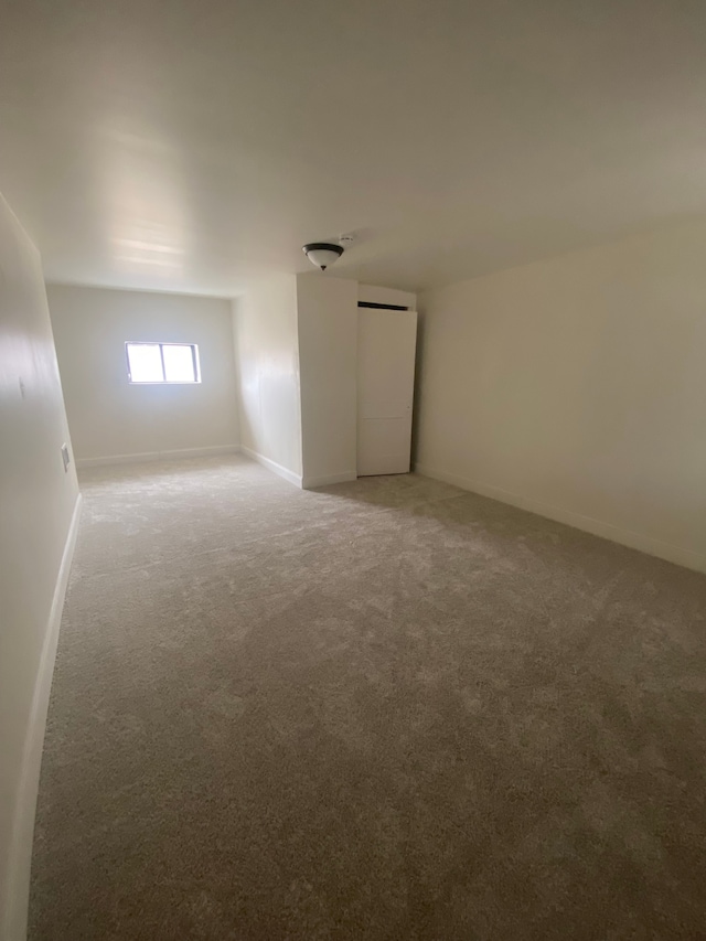 unfurnished room featuring baseboards and light colored carpet