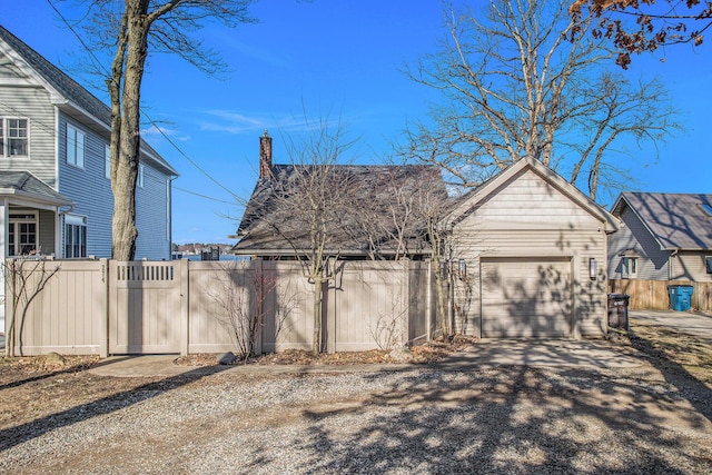 exterior space featuring driveway, a gate, fence, and a garage