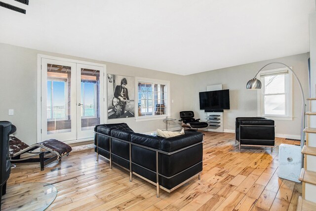 living area with baseboards, visible vents, light wood-style flooring, and french doors