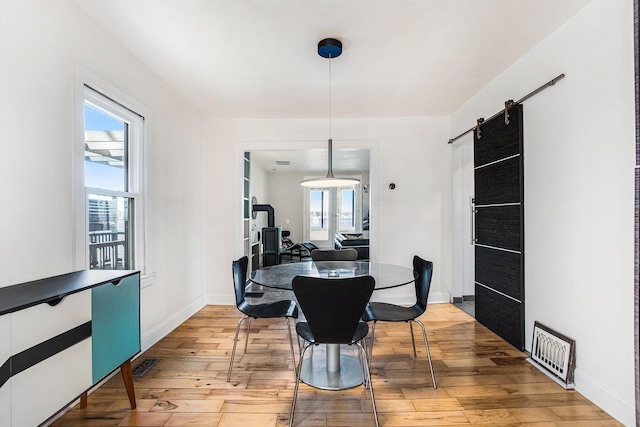 dining room with baseboards, a barn door, light wood finished floors, and visible vents