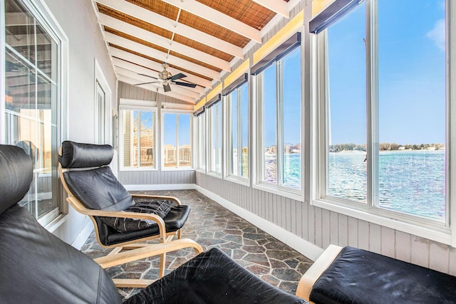 sunroom / solarium featuring baseboards, vaulted ceiling with beams, stone flooring, and ceiling fan