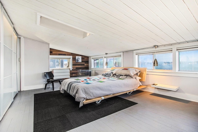 bedroom featuring hardwood / wood-style floors, attic access, multiple windows, and lofted ceiling