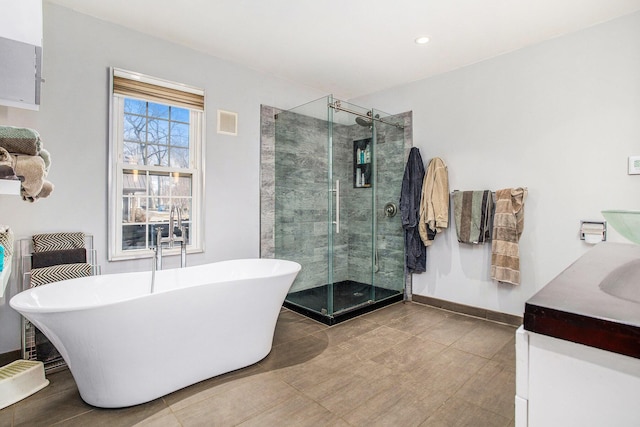 full bath with vanity, baseboards, a shower stall, visible vents, and a freestanding bath