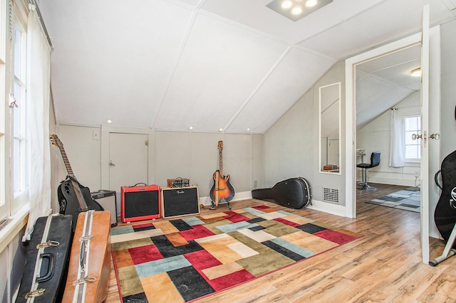 recreation room featuring lofted ceiling, visible vents, and wood finished floors