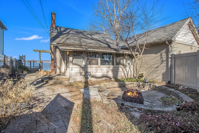 rear view of house featuring a chimney, fence, and a fire pit