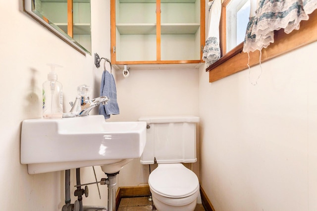 half bathroom featuring baseboards and toilet