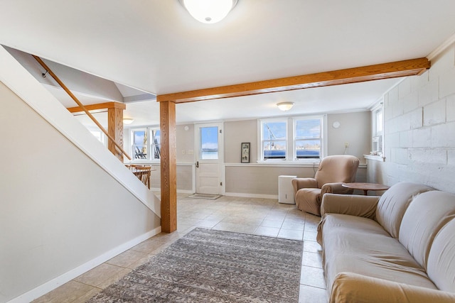 living room featuring baseboards, concrete block wall, stairway, and light tile patterned floors
