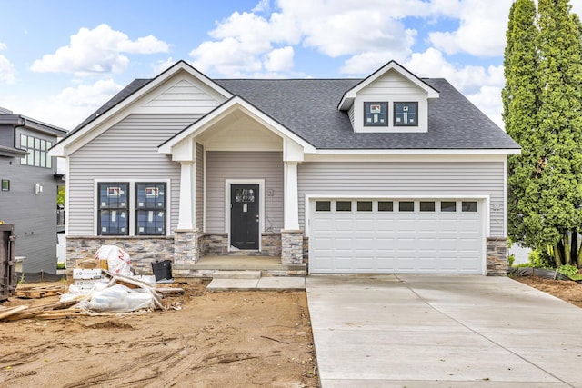 215 Nottingham Dr, Brooklyn, MI 49230 - craftsman house with stone siding, driveway, roof with shingles, and a garage