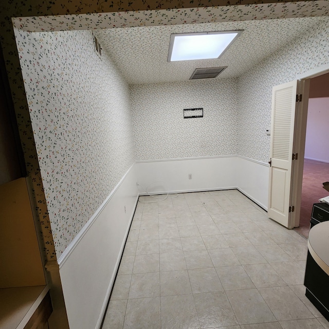 unfurnished room featuring light tile patterned floors, visible vents, and wallpapered walls