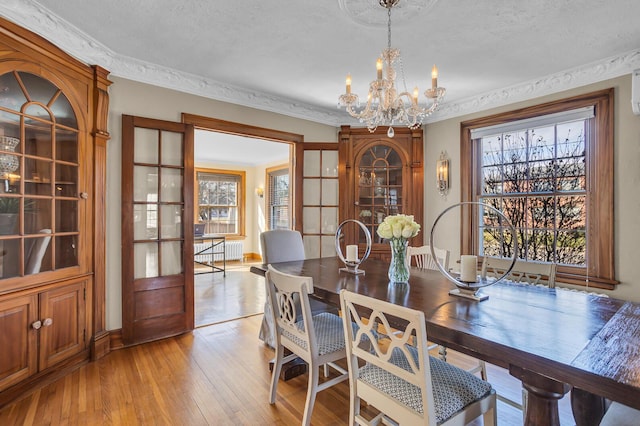 1515 W Franklin St, Jackson, MI 49203 - dining room with a textured ceiling, baseboards, ornamental molding, light wood-style floors, and a notable chandelier