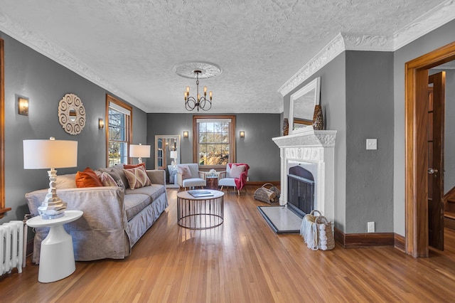 1515 W Franklin St, Jackson, MI 49203 - living room featuring a textured ceiling, a chandelier, a fireplace with raised hearth, wood finished floors, and radiator
