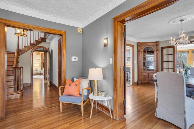 1515 W Franklin St, Jackson, MI 49203 - living area featuring stairs, an inviting chandelier, a textured ceiling, arched walkways, and wood finished floors