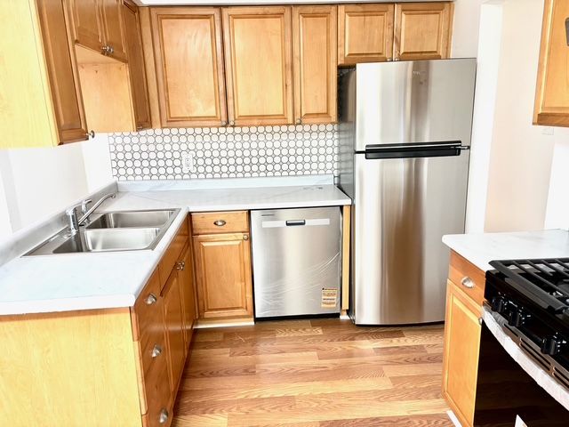 35030 Michelle Dr, Romulus, MI 48174 - kitchen featuring light countertops, a sink, stainless steel appliances, light wood finished floors, and backsplash